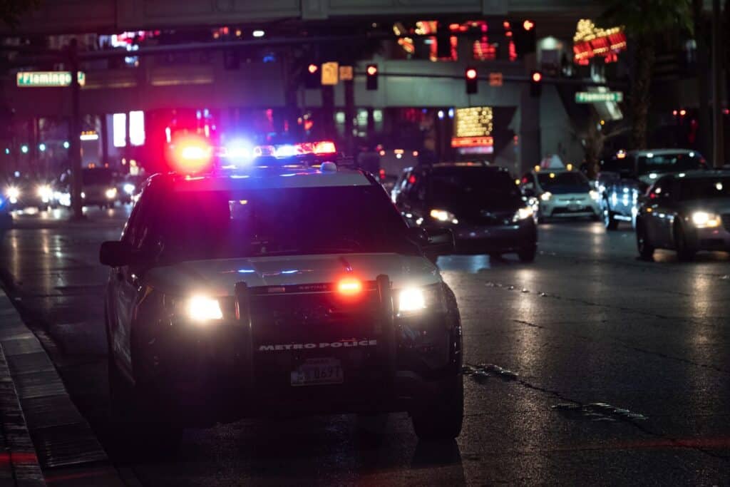 A police car with flashing lights in a busy city street at night.